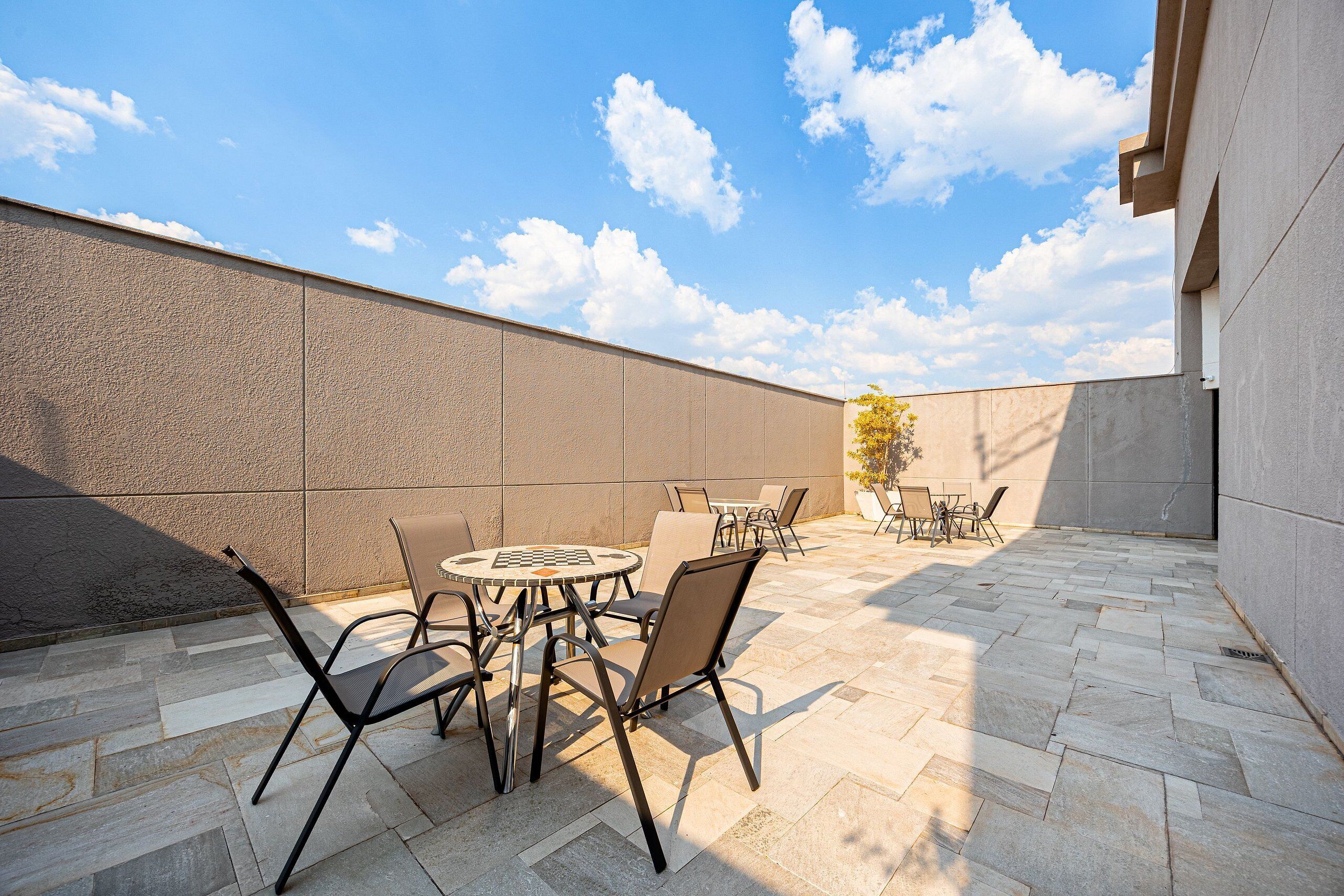An outdoor patio with stone flooring, metal chairs, and a round table.
