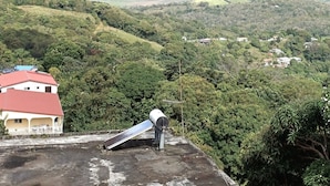 Ein Gebäude mit rotem Dach, umgeben von üppiger Vegetation und Blick auf eine ferne Stadt.