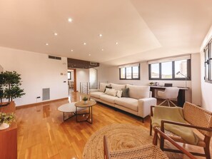 A spacious living area with a sofa, a round coffee table, and a wicker chair. - Bravissimo Plaça Catalunya 10, Duplex Penthouse with 3 bedrooms (Girona)