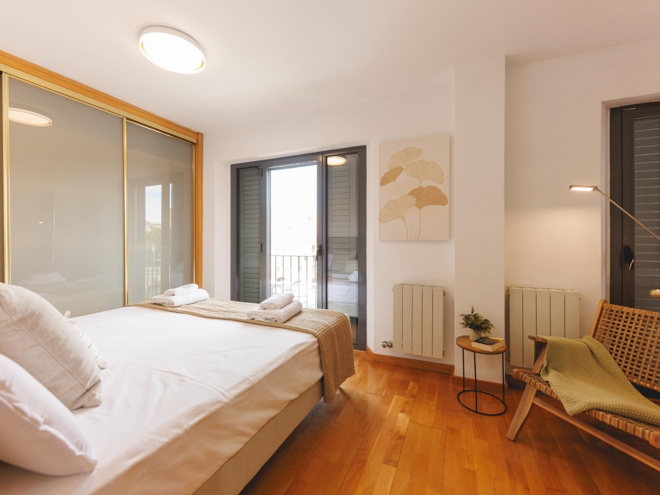 A bedroom with a bed, a chair, a radiator, and a door leading to a balcony.