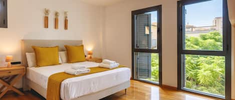 A bedroom with a bed, bedside tables, a nightstand, a window with a view, and a ceiling light.