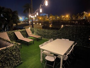 An outdoor seating area with a table and chairs, surrounded by greenery and a view of a water body. - Vrbo Property (Hollywood)