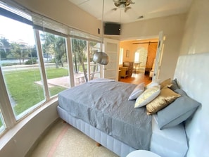 A bedroom with a large bed, a view of the outdoors, and a dining area in the background. - Vrbo Property (Hollywood)