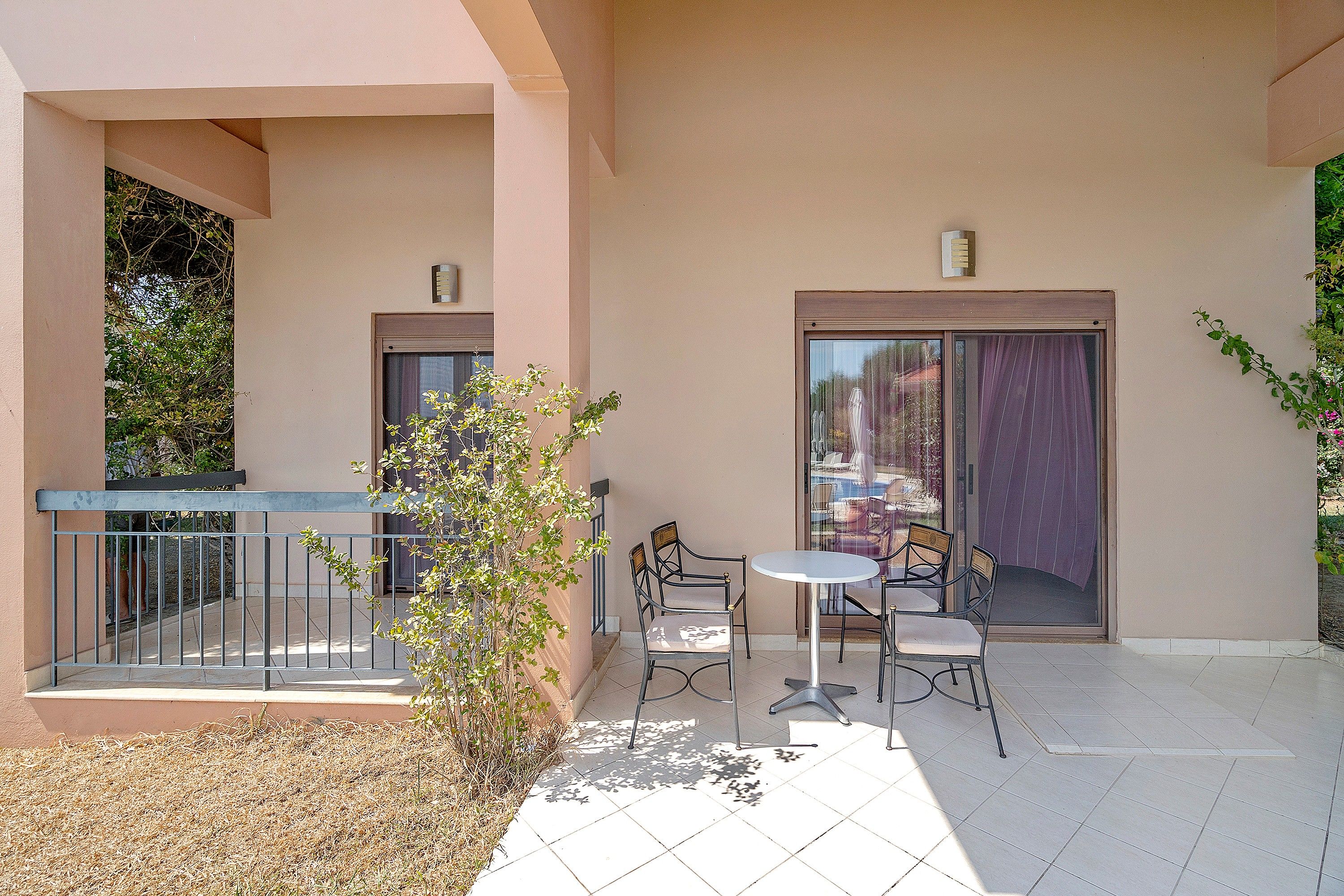 A balcony with a metal railing, a small table, and two chairs.