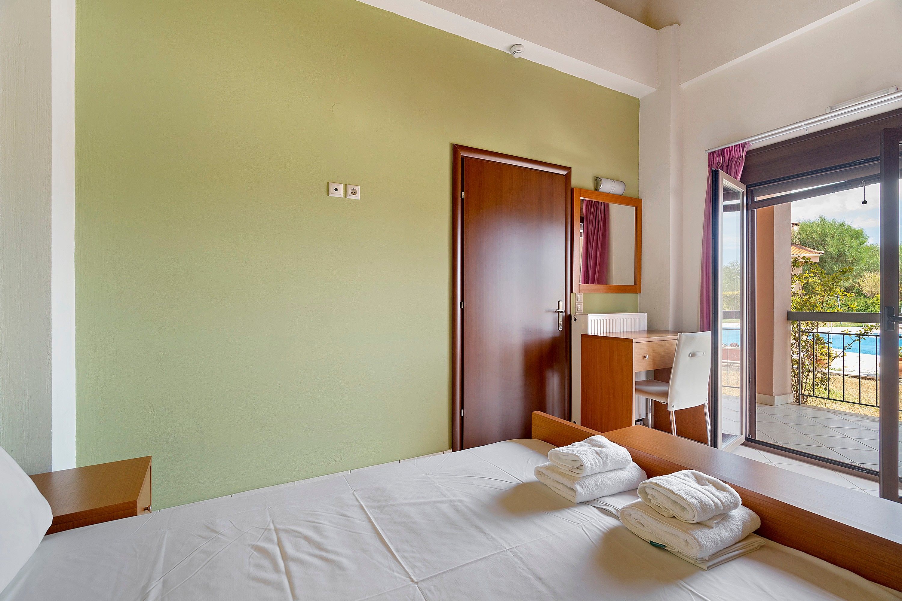 Ein Hotelzimmer mit Bett, Schreibtisch, Stuhl, Fenster mit Blick und Tür.