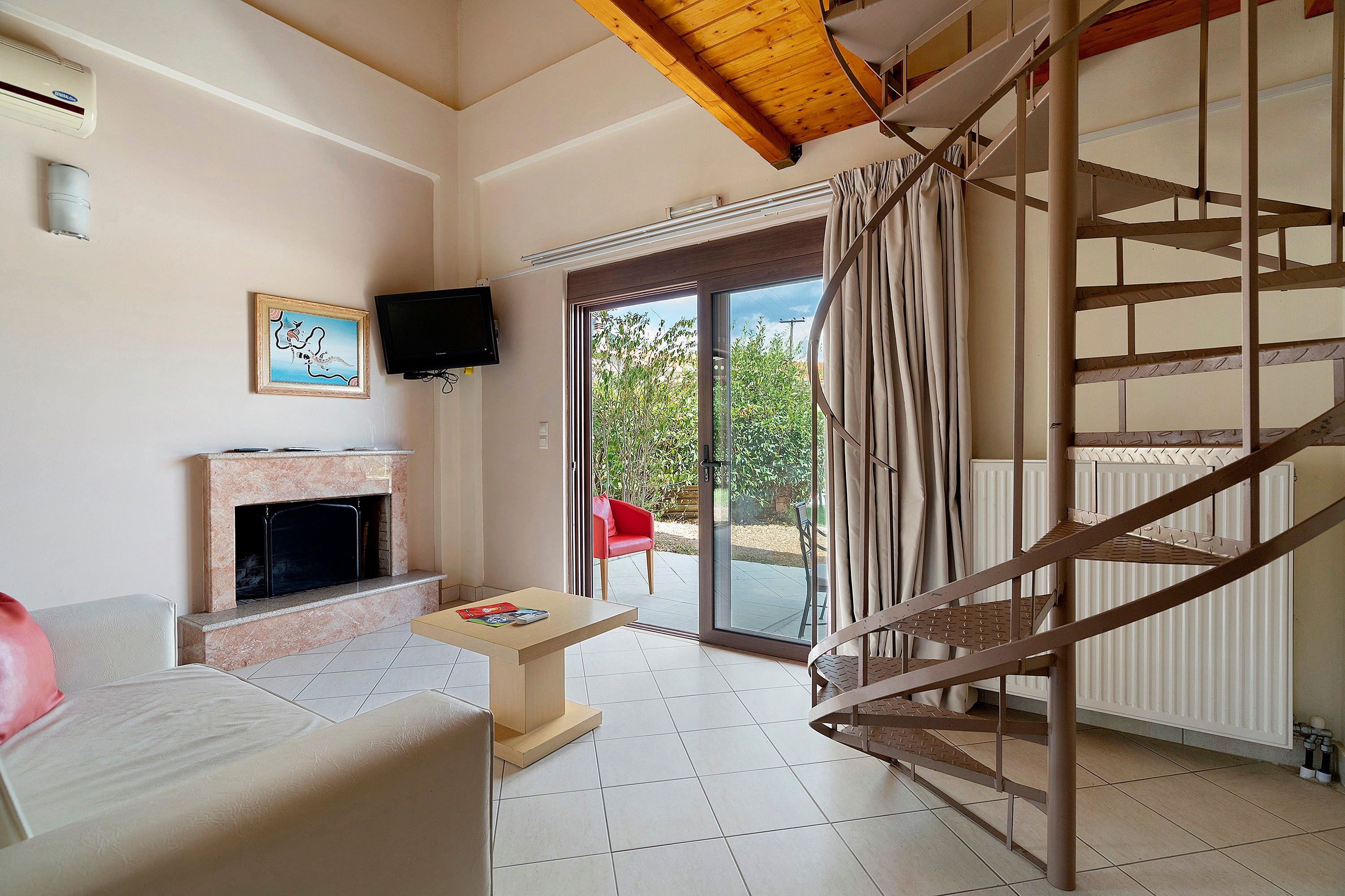 Ein Wohnzimmer mit Kamin, Fernseher und einer Treppe, die zu einem Außenbereich führt.