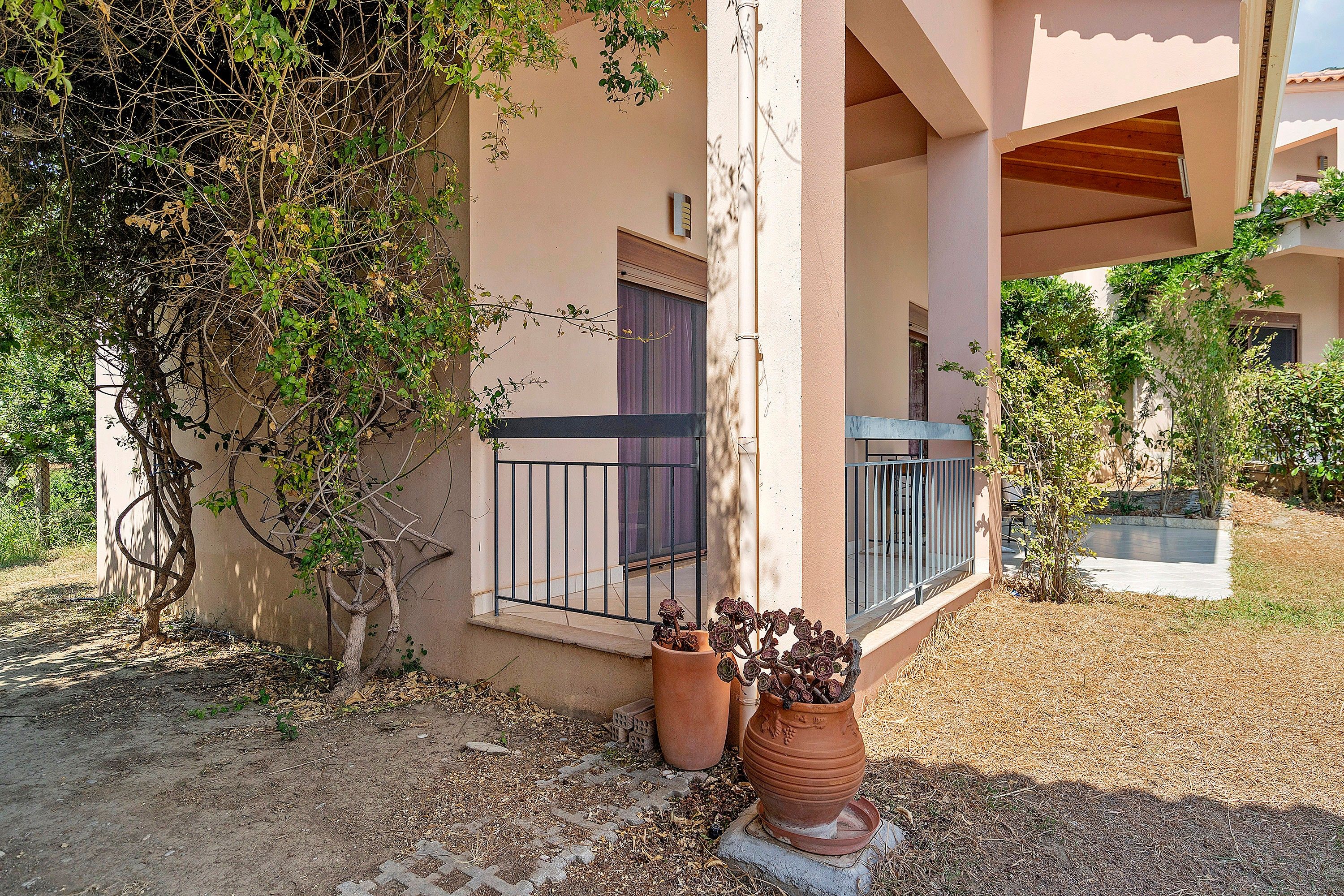 A building with a balcony, a potted plant, and a tree.