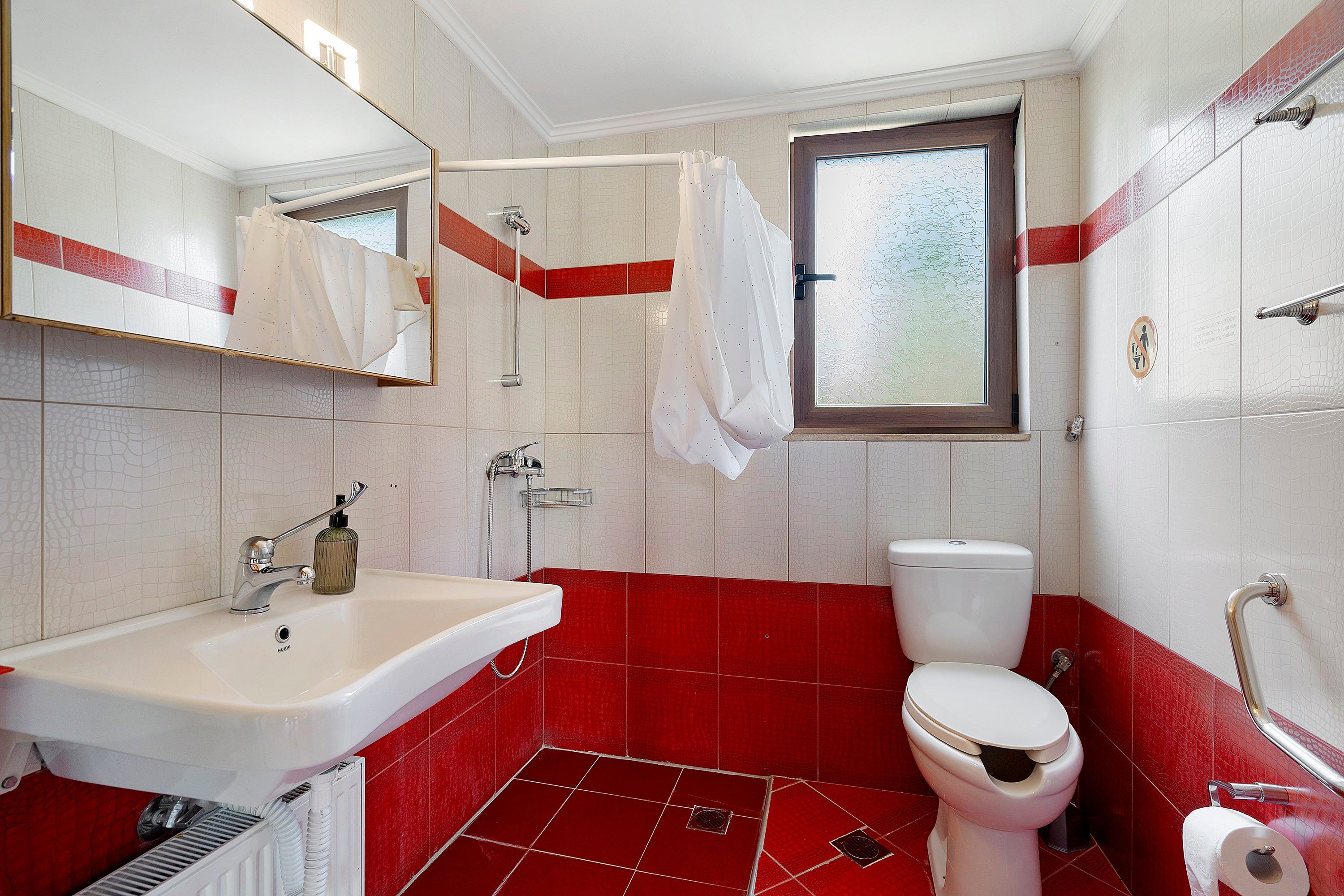Un baño con lavamanos blanco, inodoro y zona de ducha.