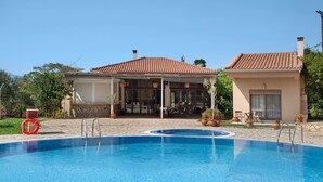A swimming pool with a lifebuoy, a covered patio, and a house with a tiled roof. - Villa 'Ariadni' in Marathiás (Marathiás)