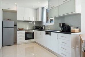A modern kitchen with white cabinetry, a built-in oven, a microwave, and a coffee maker.