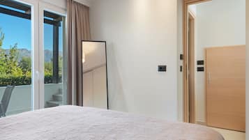 A bedroom with a bed, a sliding glass door to a balcony, and a wooden door.