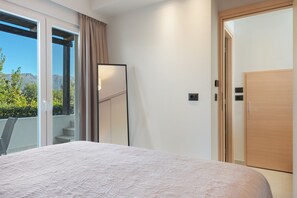 A bedroom with a bed, a sliding glass door to a balcony, and a wooden door.