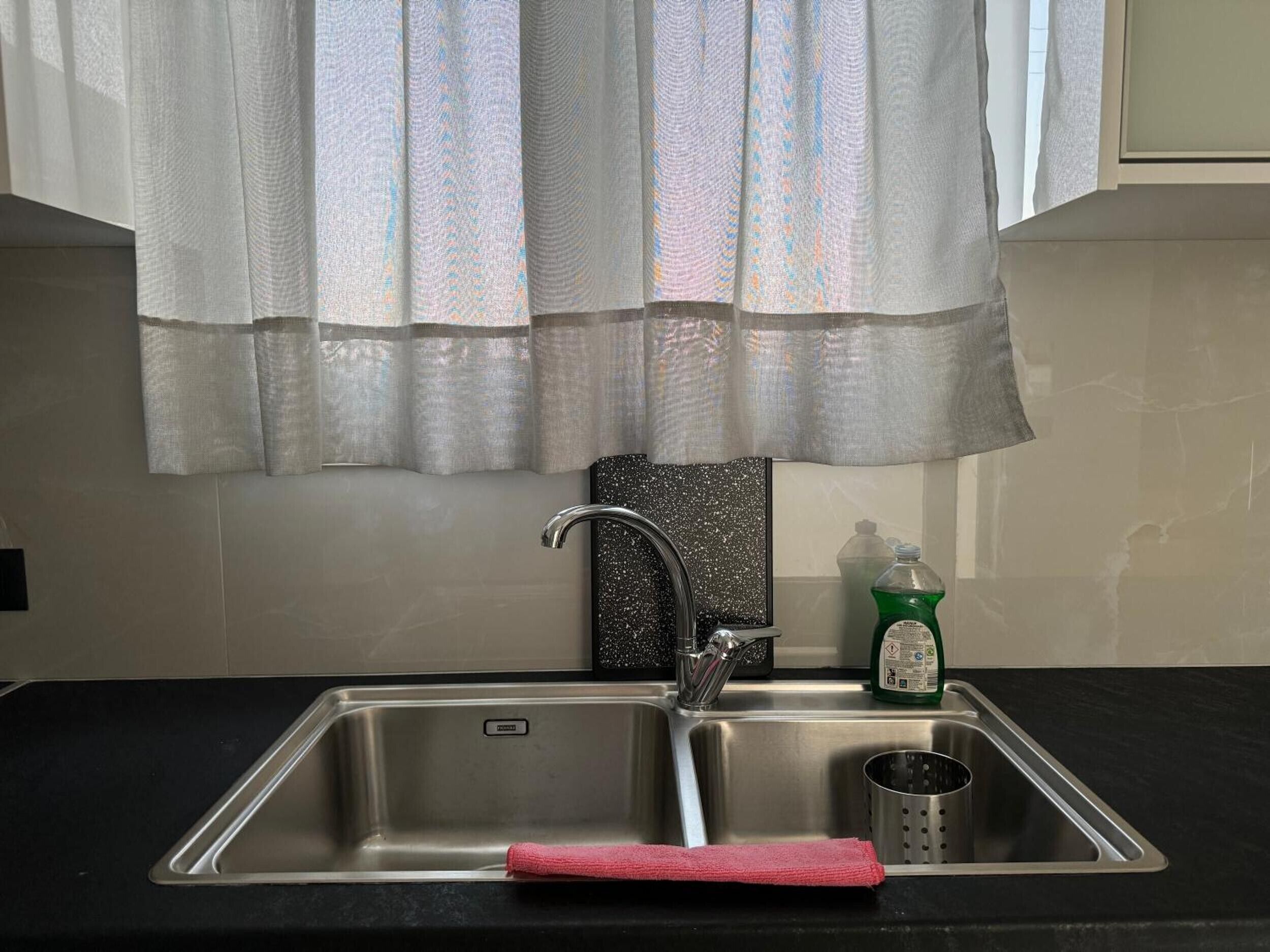 Lavello da cucina con rubinetto in acciaio inox, erogatore di sapone e asciugamano rosso.