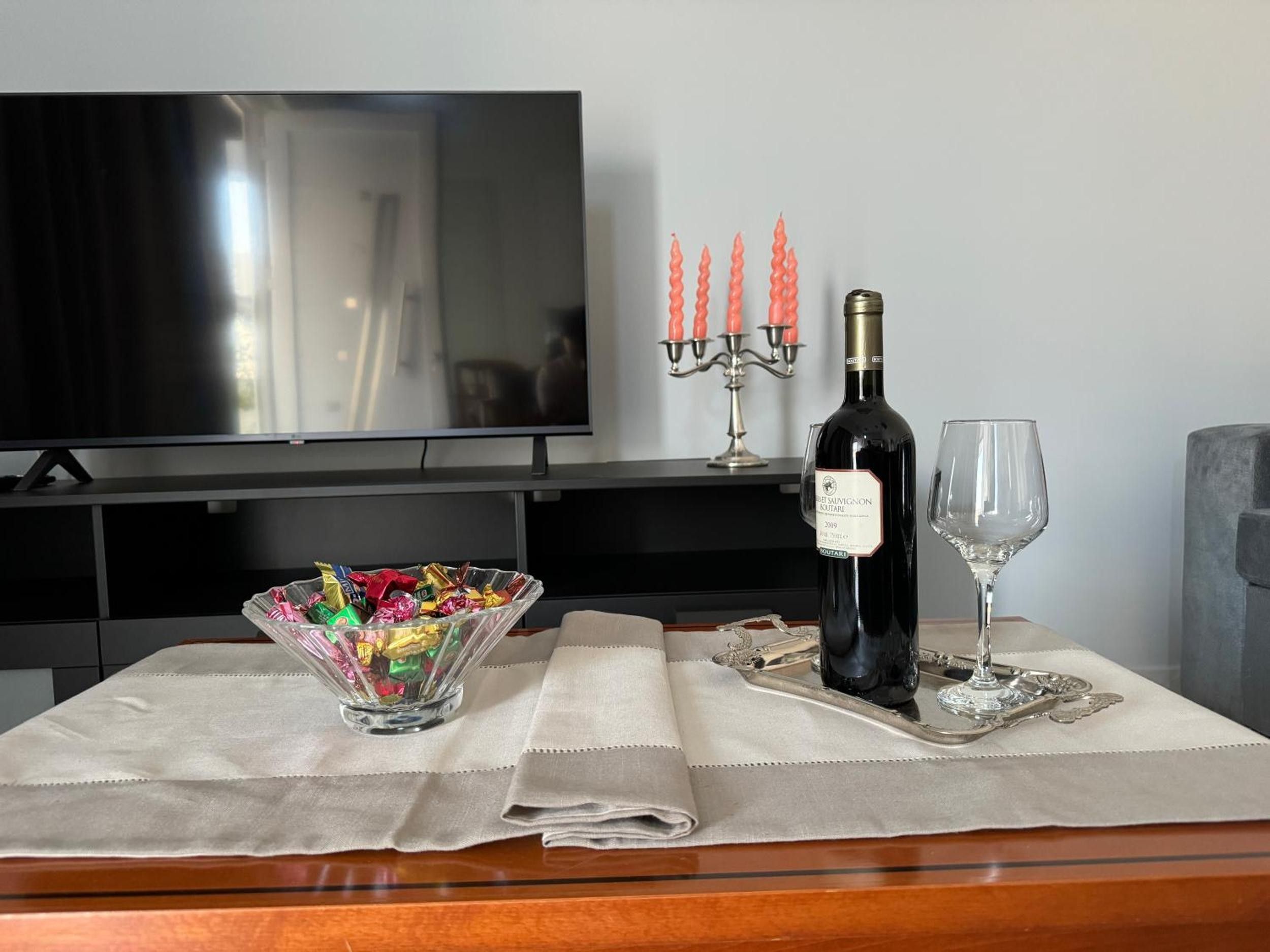 Uma mesa de jantar com uma garrafa de vinho, um copo, um candelabro e uma tigela de petiscos.