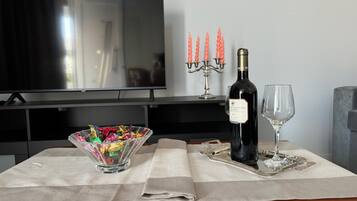 Uma mesa de jantar com uma garrafa de vinho, um copo, um candelabro e uma tigela de petiscos.