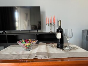 A dining table with a bottle of wine, a glass, a candelabra, and a bowl of snacks.