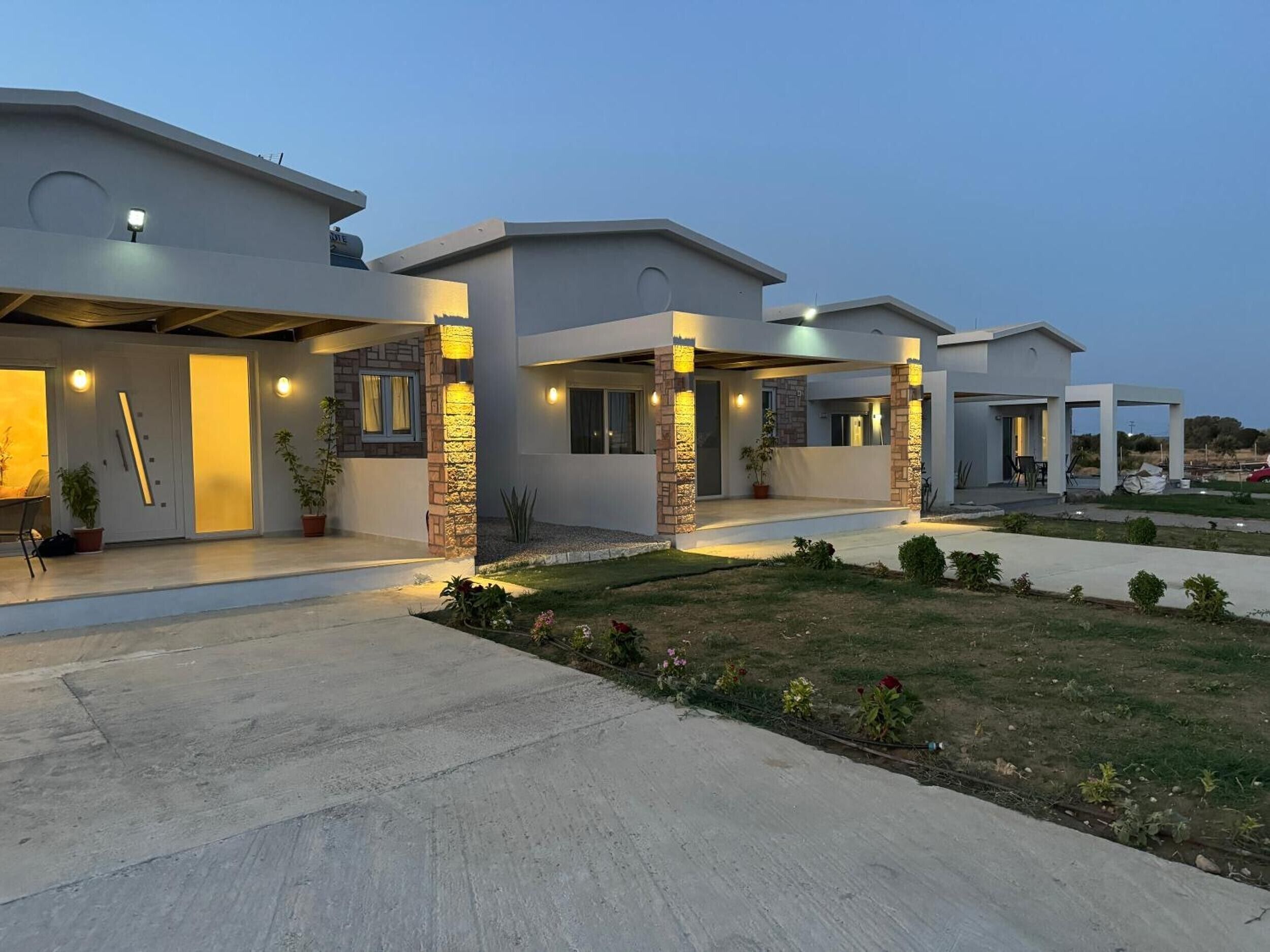 A modern residential building with a covered patio area and a well-maintained garden.