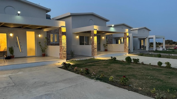 A modern residential building with a covered patio area and a well-maintained garden.