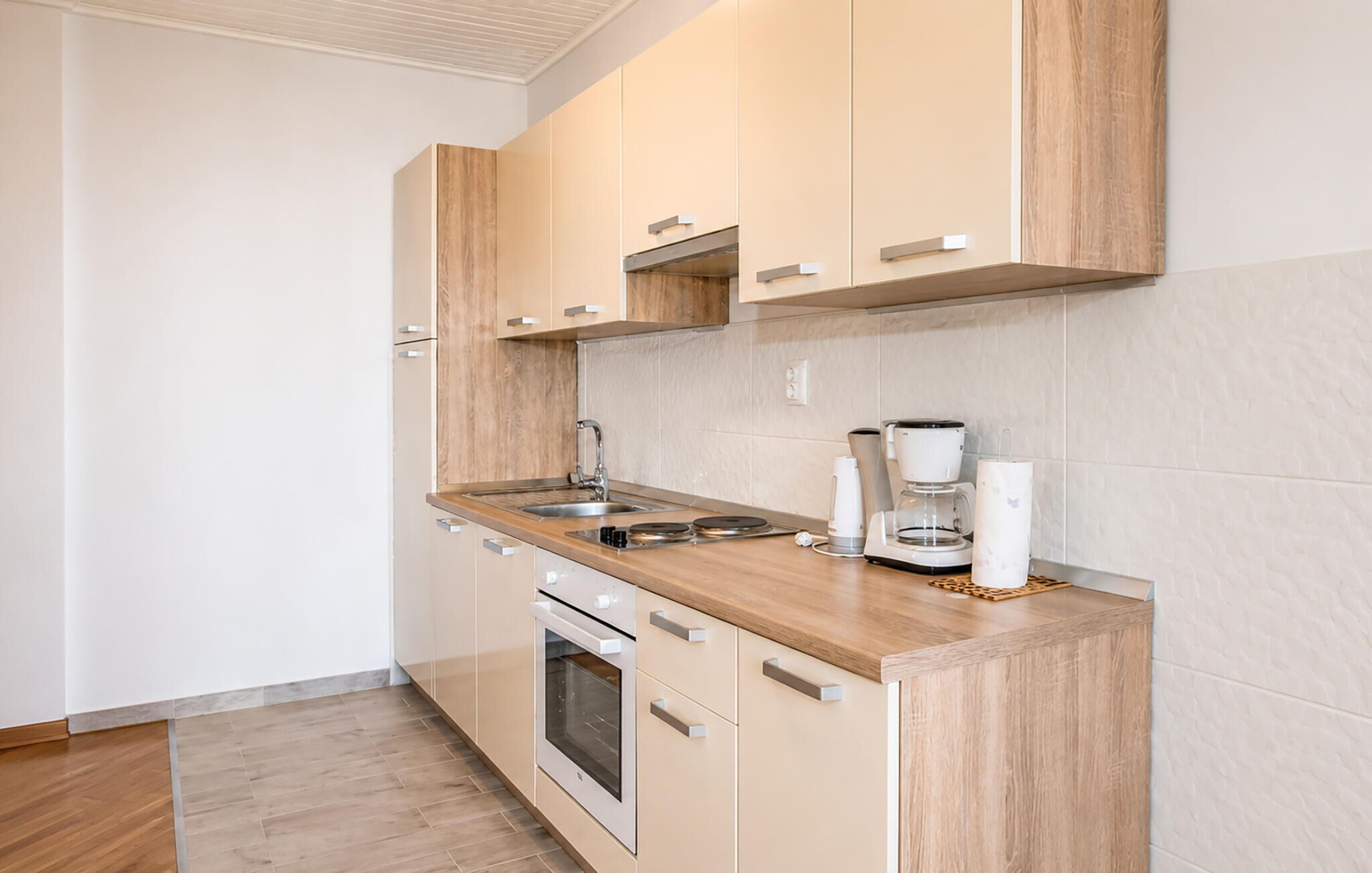 Une cuisine moderne avec des meubles en bois, un évier en acier inoxydable et un four encastré.