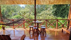 Eine Holzterrasse mit einer Hängematte, Stühlen und einem Tisch.
