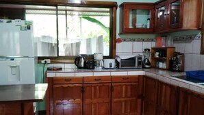 Eine Küche mit Holzschränken, einem Kühlschrank, einer Mikrowelle und einer Kaffeemaschine.