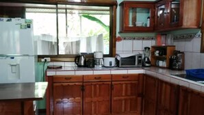 Eine Küche mit Holzausstattung, einem Kühlschrank, einer Mikrowelle und einer Kaffeemaschine.