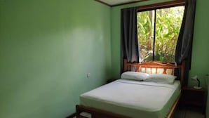 Ein Zimmer mit einem Bett, einem Vorhangfenster und Blick auf Grünflächen.