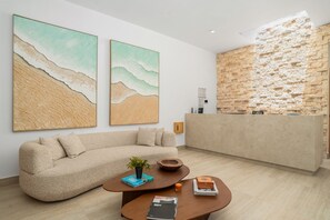 Eine moderne Hotellobby mit einer Couch, einem Couchtisch und einem Empfangsbereich vor einer strukturierten Wand.
