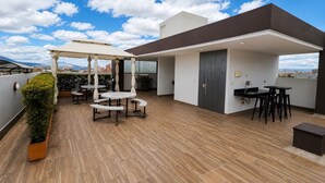 Una terrazza sul tetto con una pergola, un'area salotto e vista sulla città.