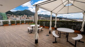An outdoor terrace with tables and chairs, a view of a cityscape and mountains in the background. - Modern Studio in Chapinero | City Views & Workspace (Bogotá)