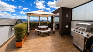 A rooftop patio with a grill, a table with chairs, and a view of the city. - Modern Studio in Chapinero | City Views & Workspace (Bogotá)