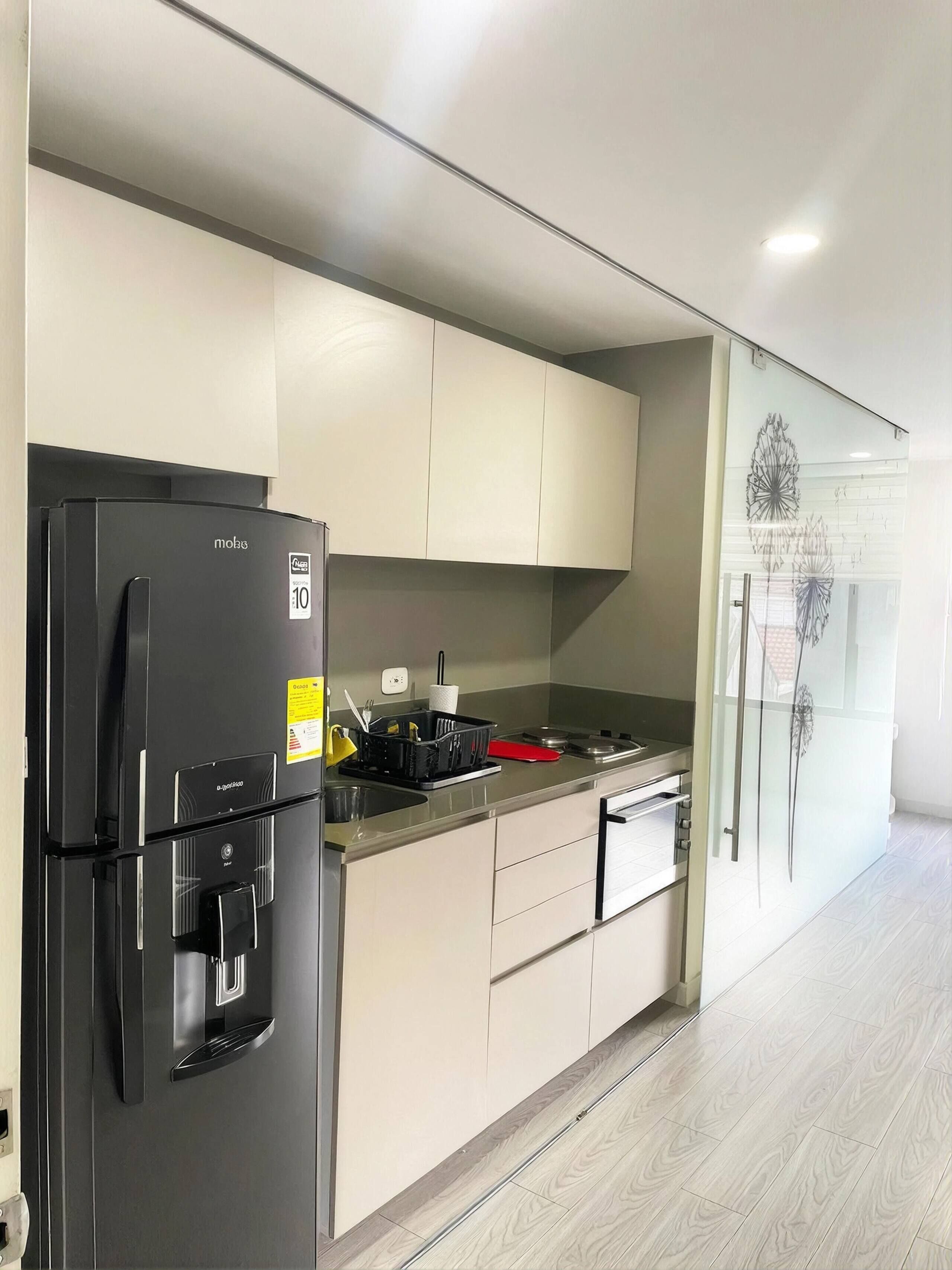 A modern kitchen with a black refrigerator, a sink, and a stove.