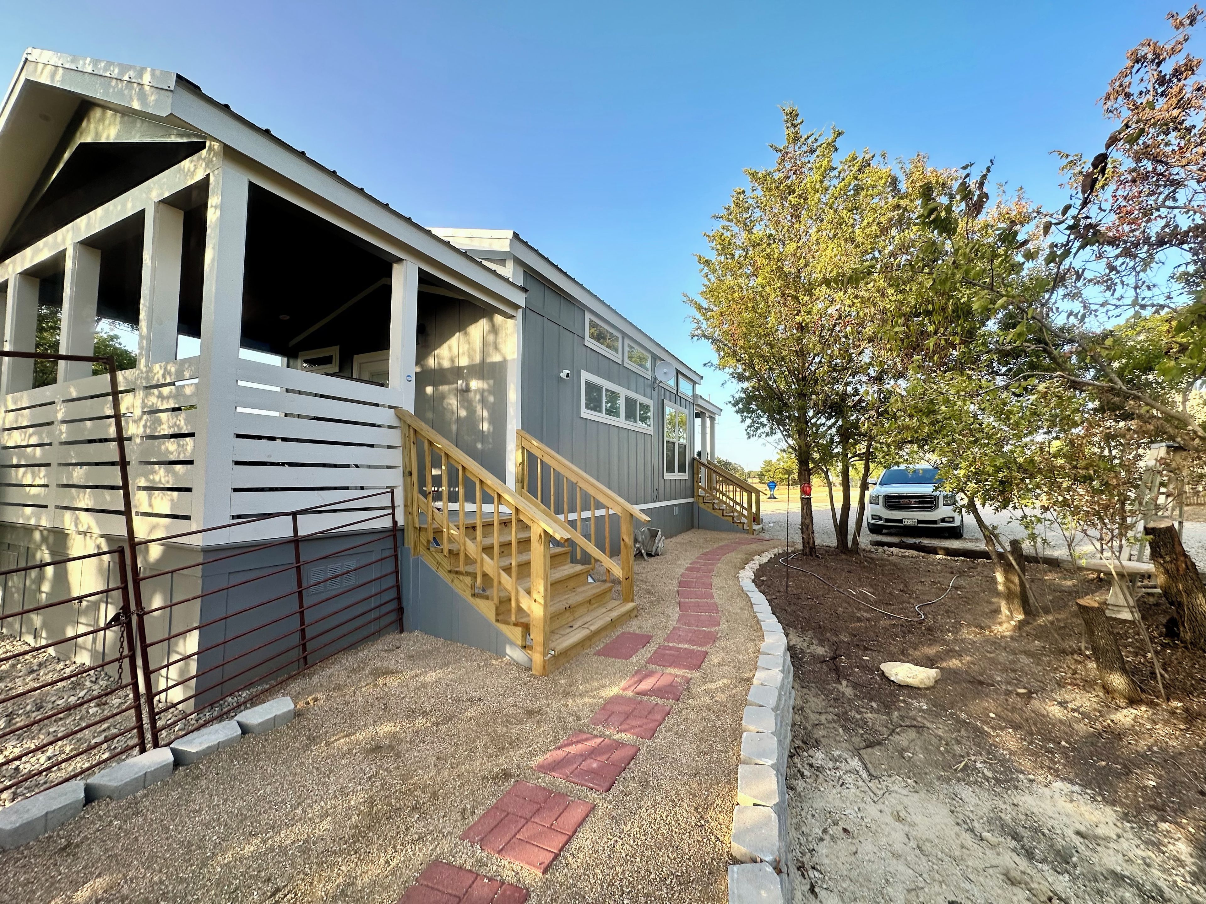A residential property with a covered porch, a staircase leading to a deck, and a driveway with a parked vehicle.