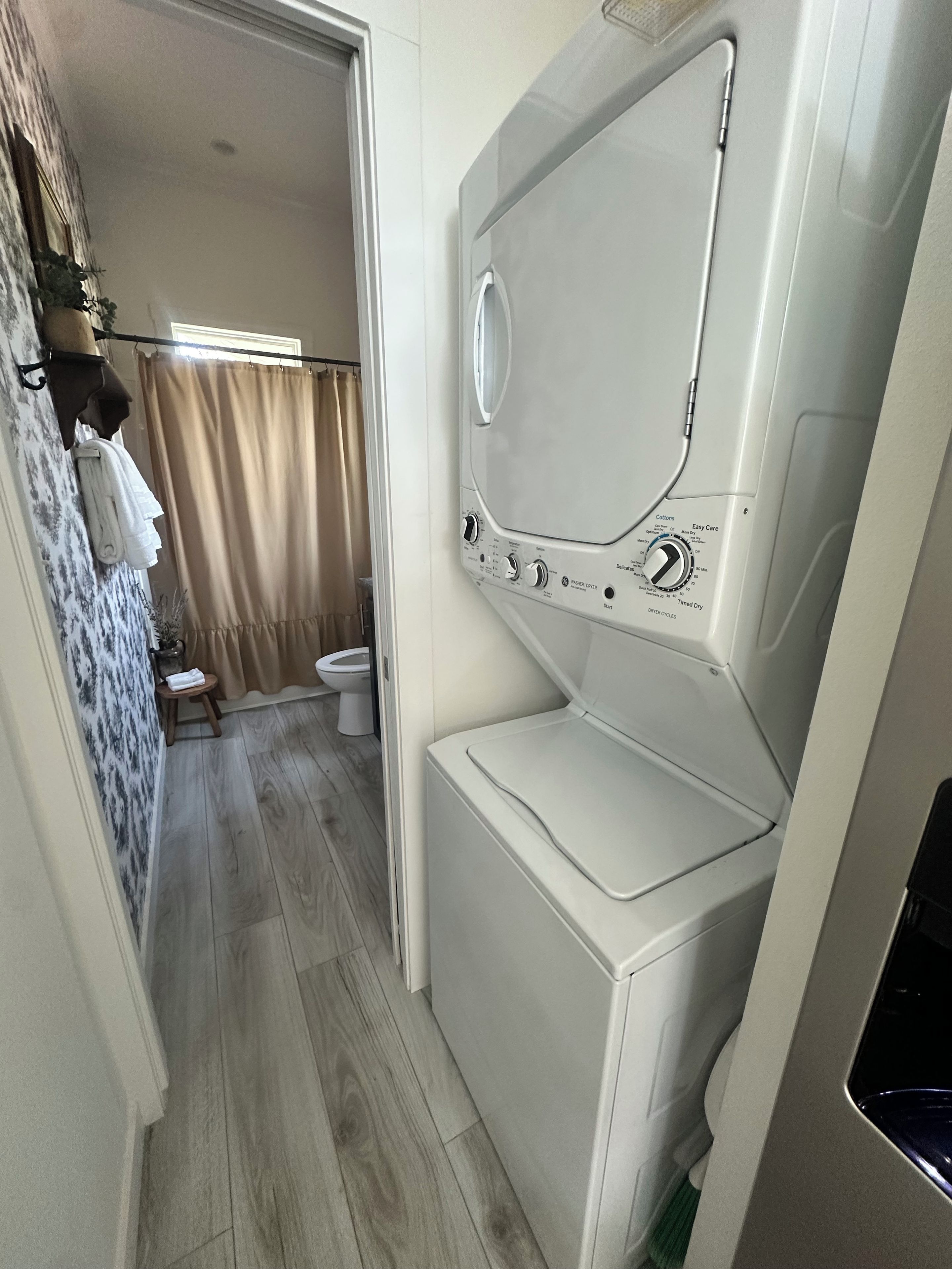A compact laundry room with a washing machine, a drying machine, and a small stool.