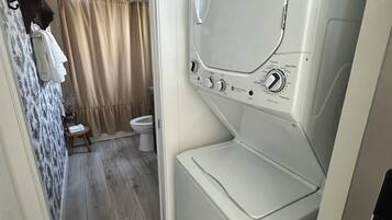 A compact laundry room with a washing machine, a drying machine, and a small stool.