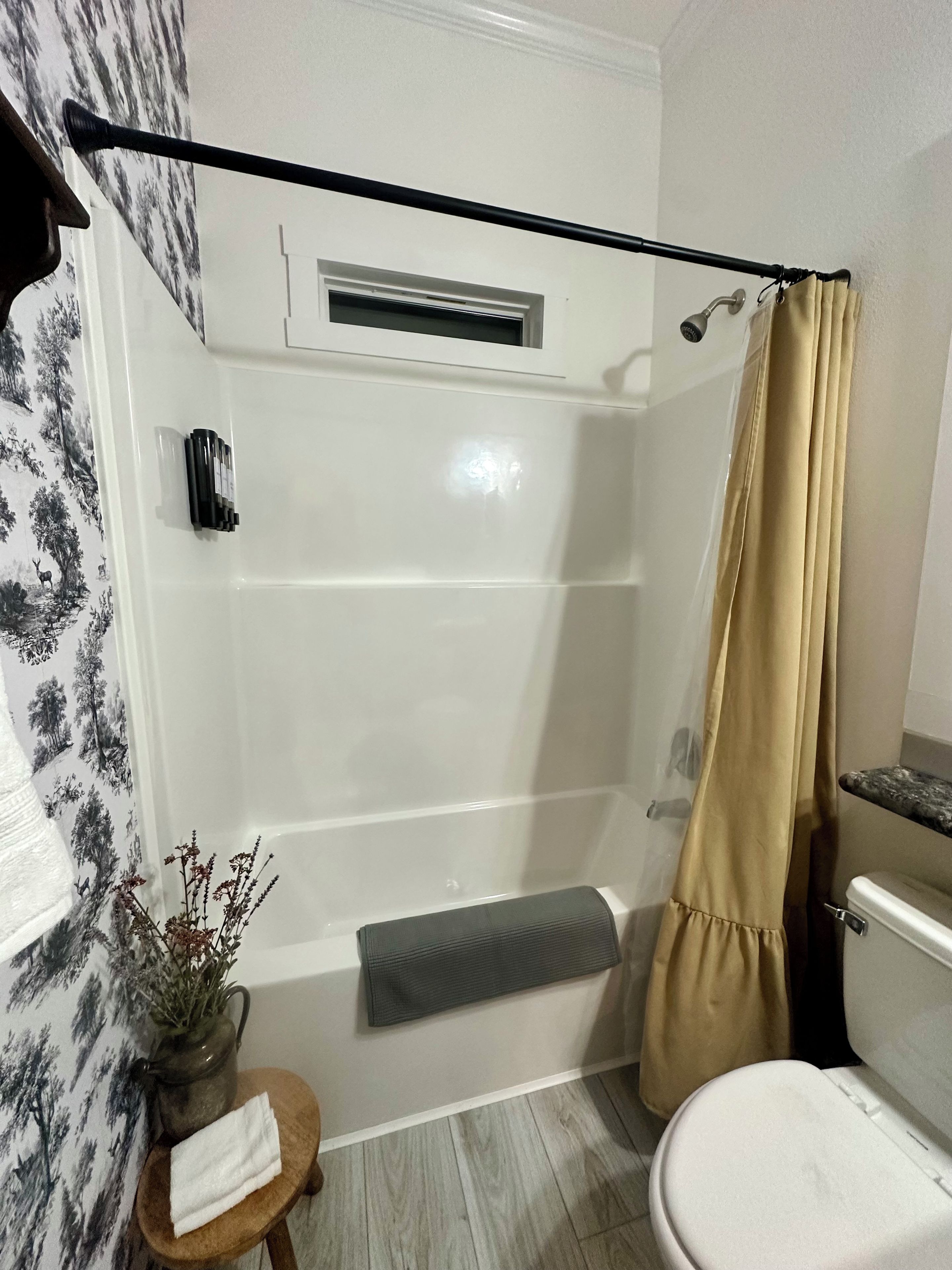 A bathroom with a shower, toilet, and a small table with a towel.