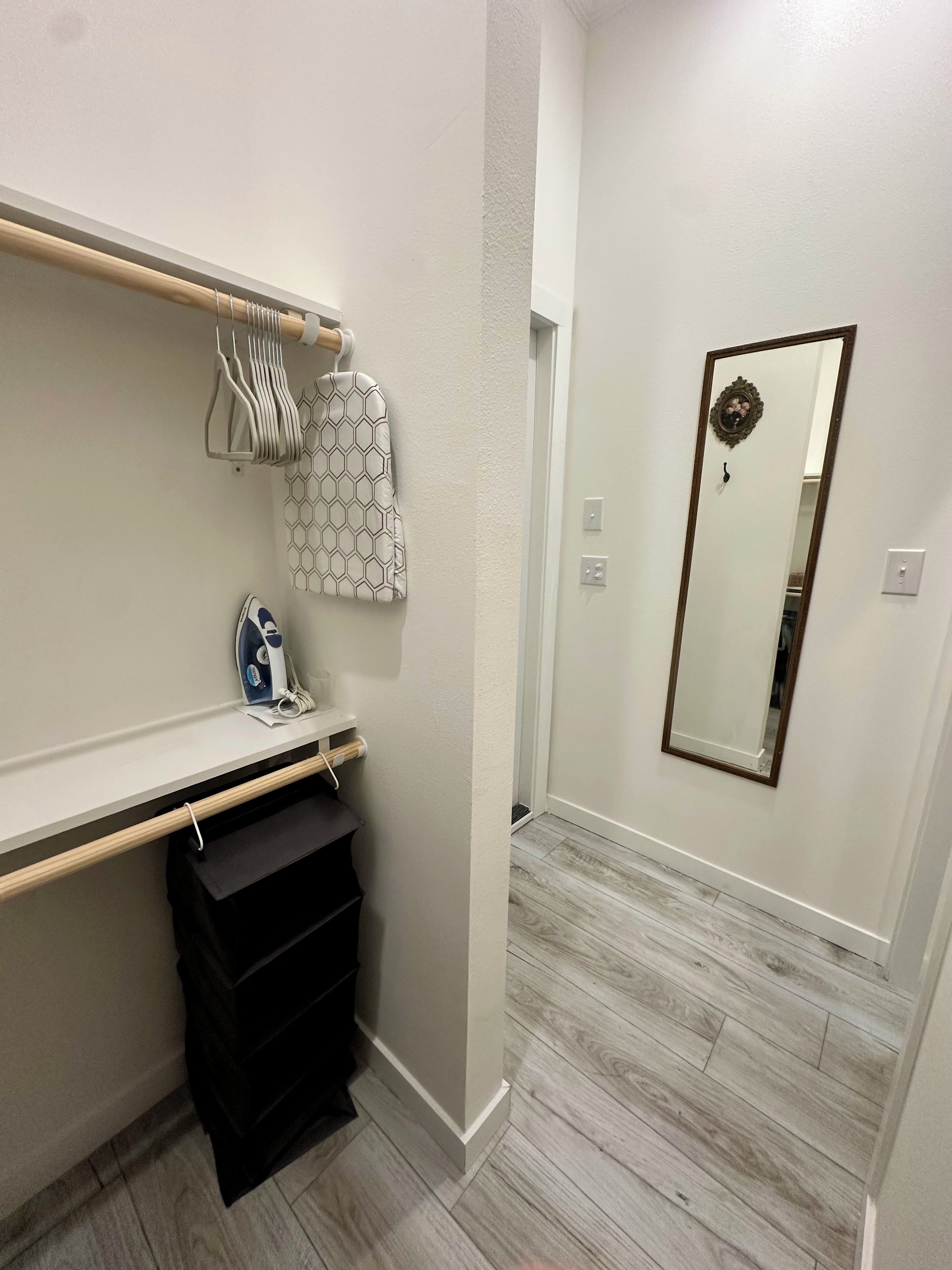 A bathroom with a wooden vanity, a mirror, and a towel rack.