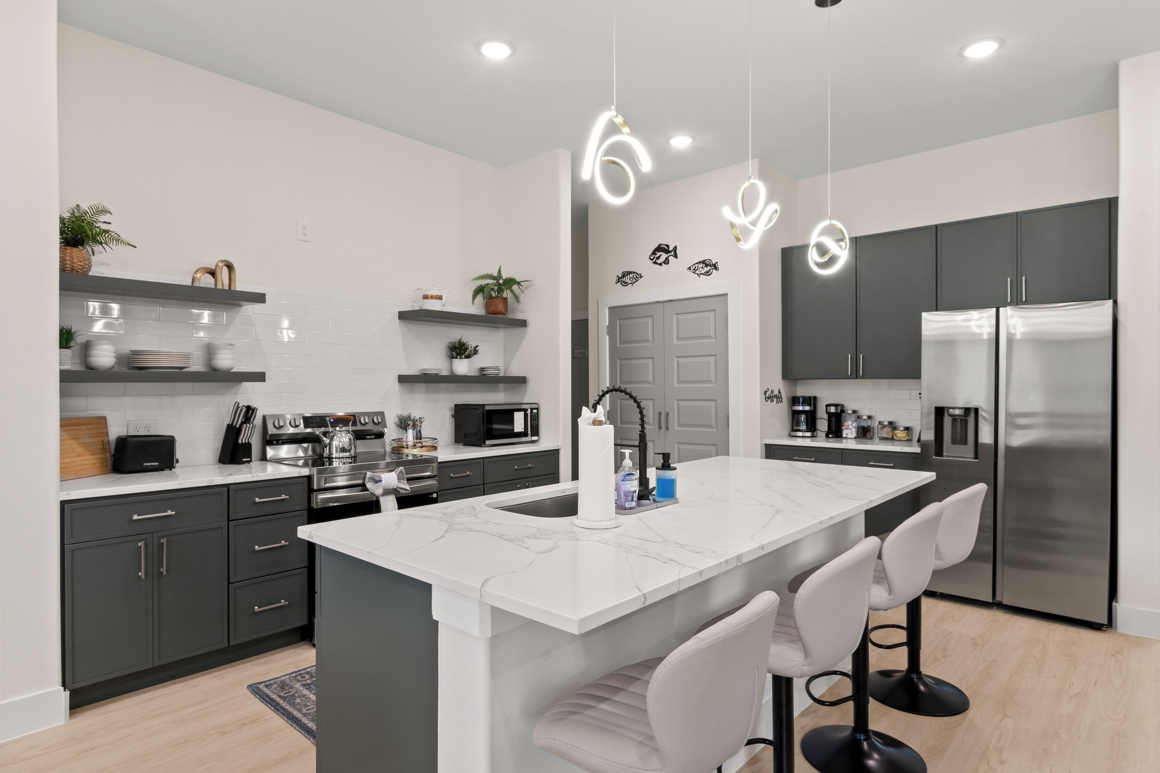 A modern kitchen with a central island, dark cabinetry, and stainless steel appliances.