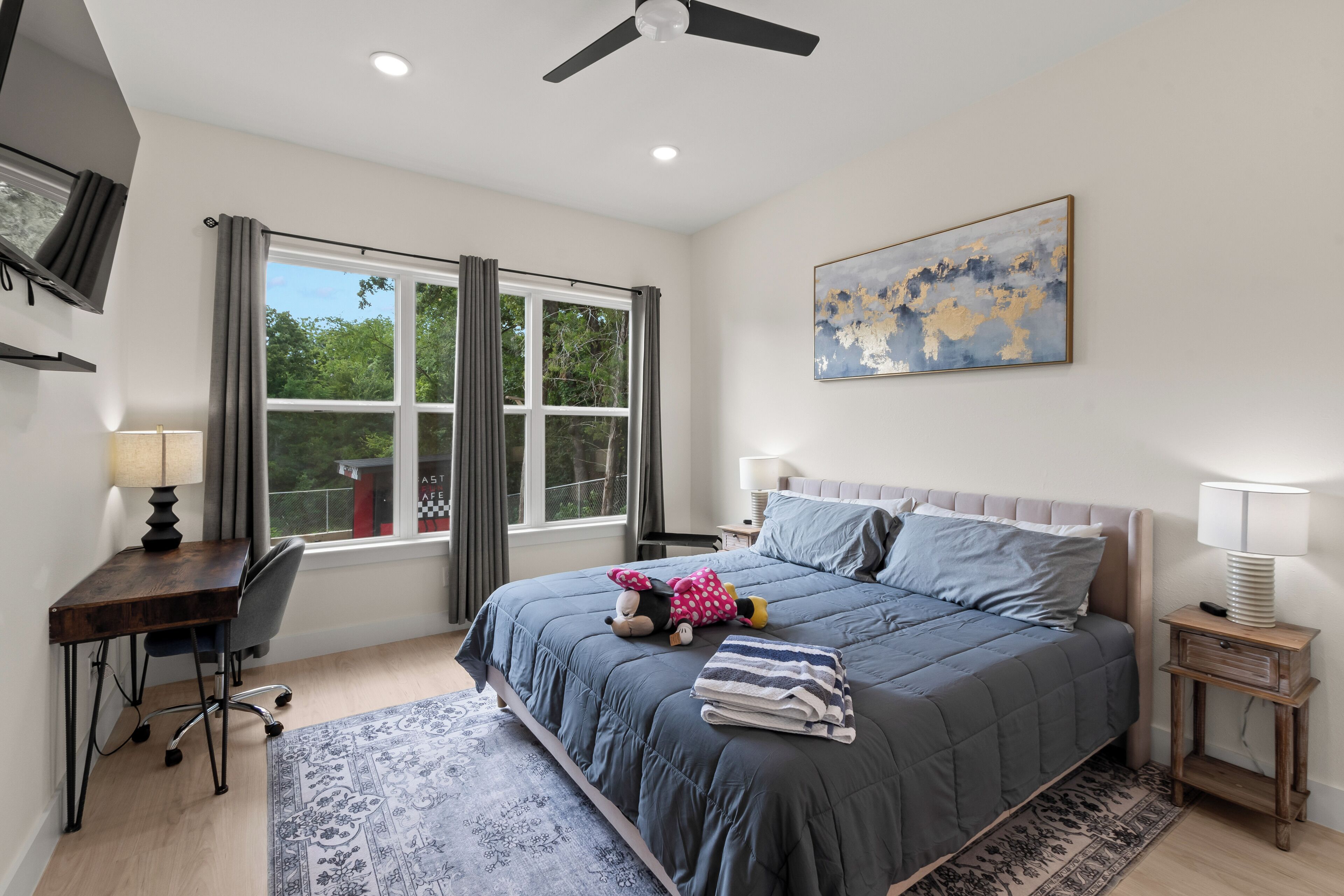 A bedroom with a bed, desk, chair, and a window with curtains.