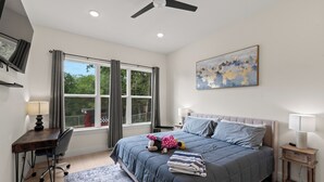A bedroom with a bed, desk, chair, and a window with curtains.