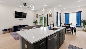A modern kitchen with a central island, built-in appliances, and a dining area with a table and chairs.
