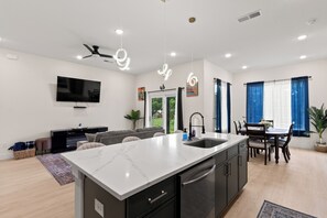 A modern kitchen with a central island, built-in appliances, and a dining area with a table and chairs.
