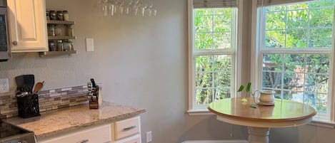 A kitchen with a built-in oven, a countertop with a knife block, and a window with a view of greenery.