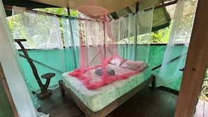 A bed with a canopy, a wooden floor, and a view of greenery outside. - Río Agujitas Rainforest Eco Lodge - Habitación Doble Deluxe (Agujitas (Drake))