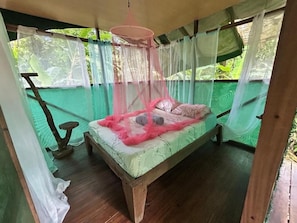 Un letto a baldacchino, pavimento in legno e vista sul verde.