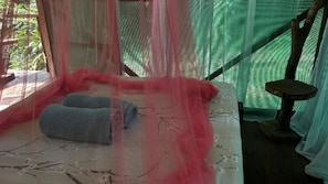 Un letto a baldacchino, un tavolino e vista sul verde circostante.
