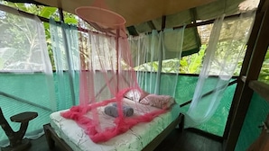 A bed with a canopy, a small table, and a view of greenery outside. - Río Agujitas Rainforest Eco Lodge - Habitación Doble Deluxe (Agujitas (Drake))