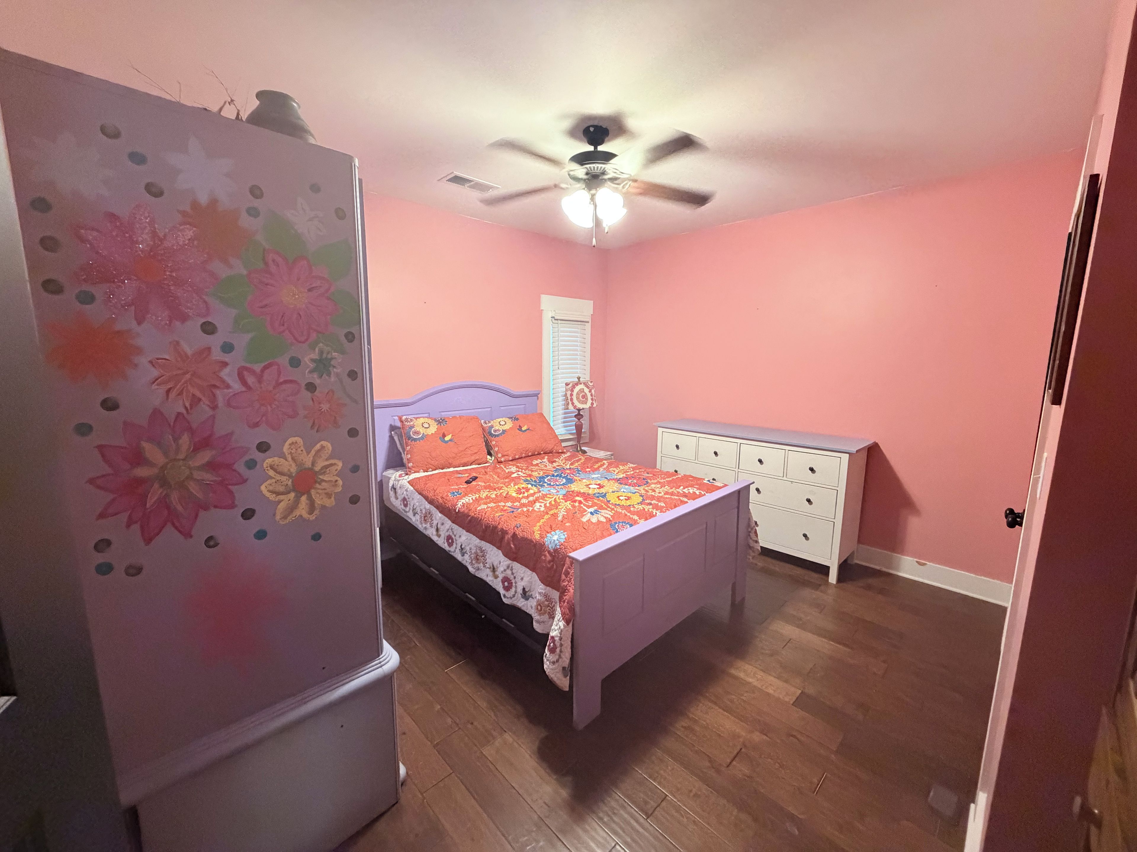 Un dormitorio con cama, cómoda y ventilador de techo.