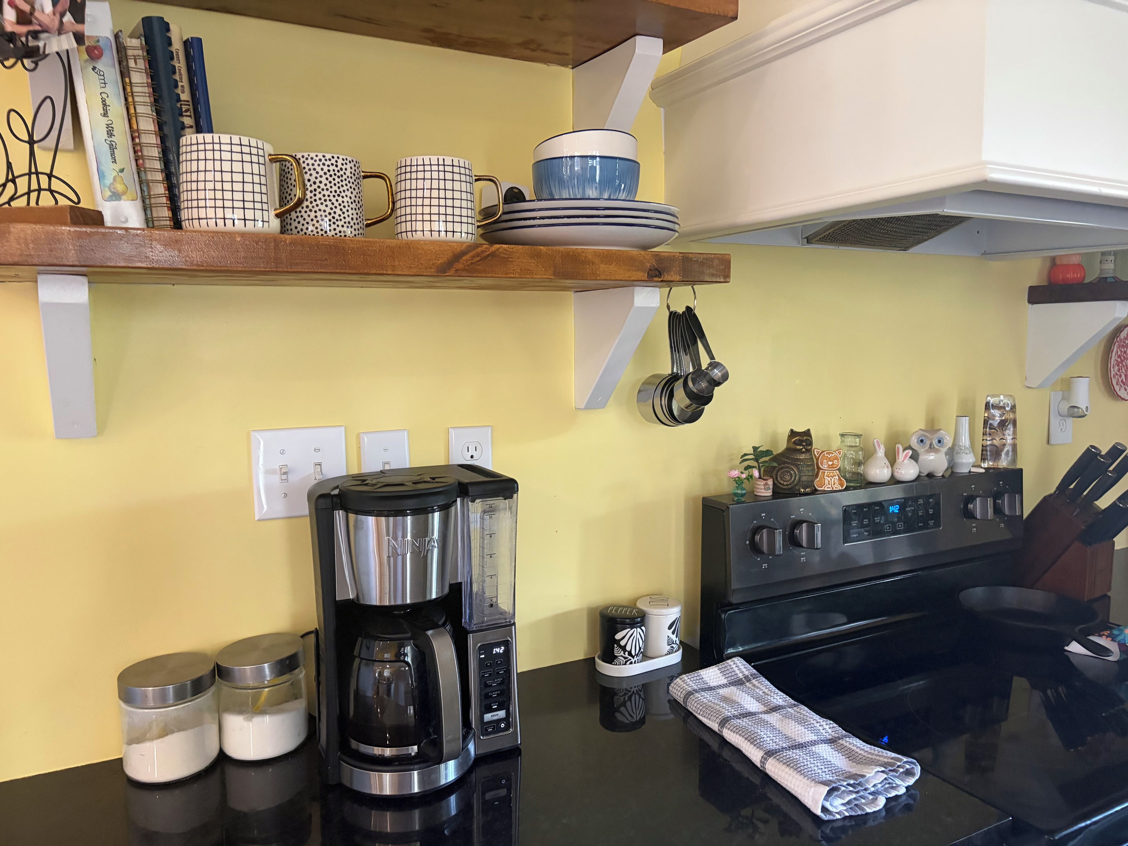 Una cocina con cafetera, estufa y varios utensilios.