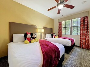 A hotel room with two beds, a ceiling fan, and a window with curtains. - 3BR Orlando Resort | Heated Pools | 3 mi Disney (Orlando)